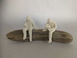 Two stoneware figures seated on driftwood